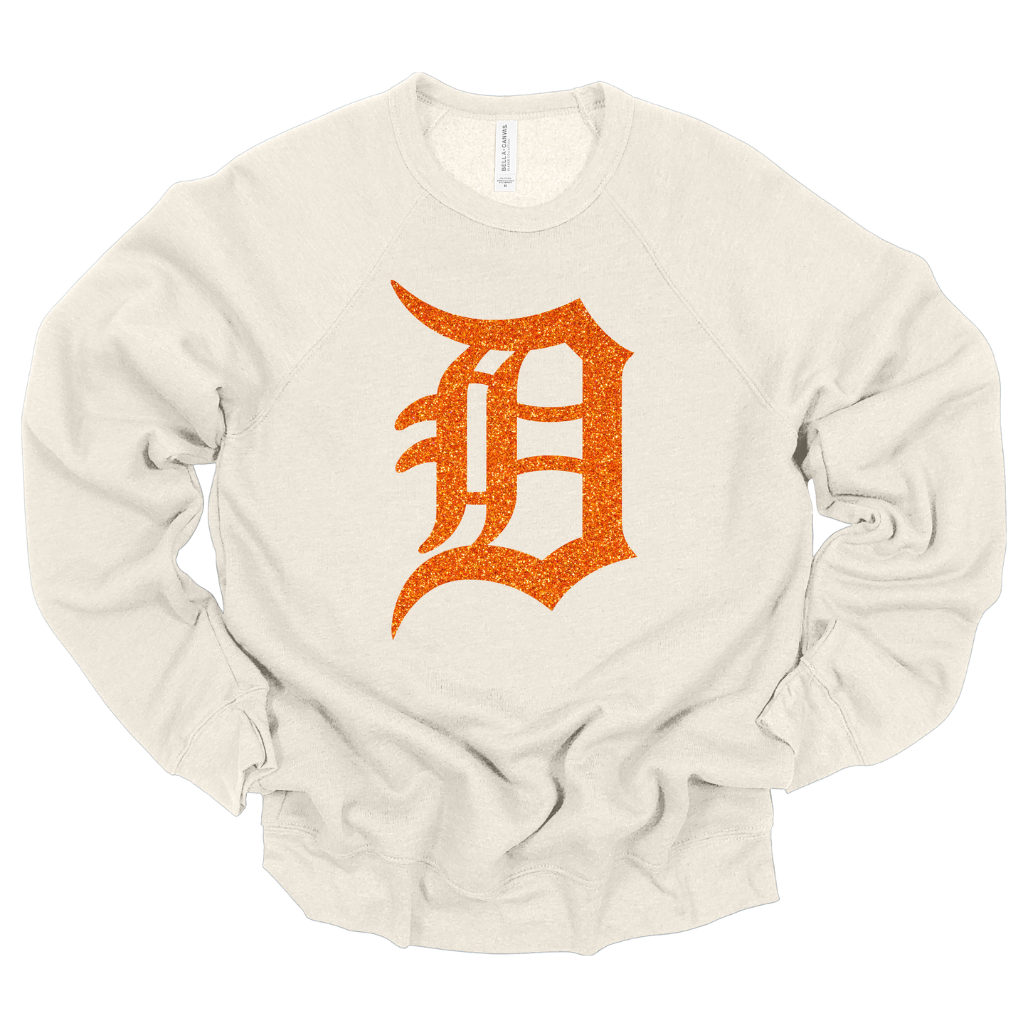 A dust colored crewneck sweatshirt featuring a bold, glitter-textured ‘D’ in a classic Detroit-style font. The design is shown in orange glitter, adding a sparkling touch to a sporty and stylish look.