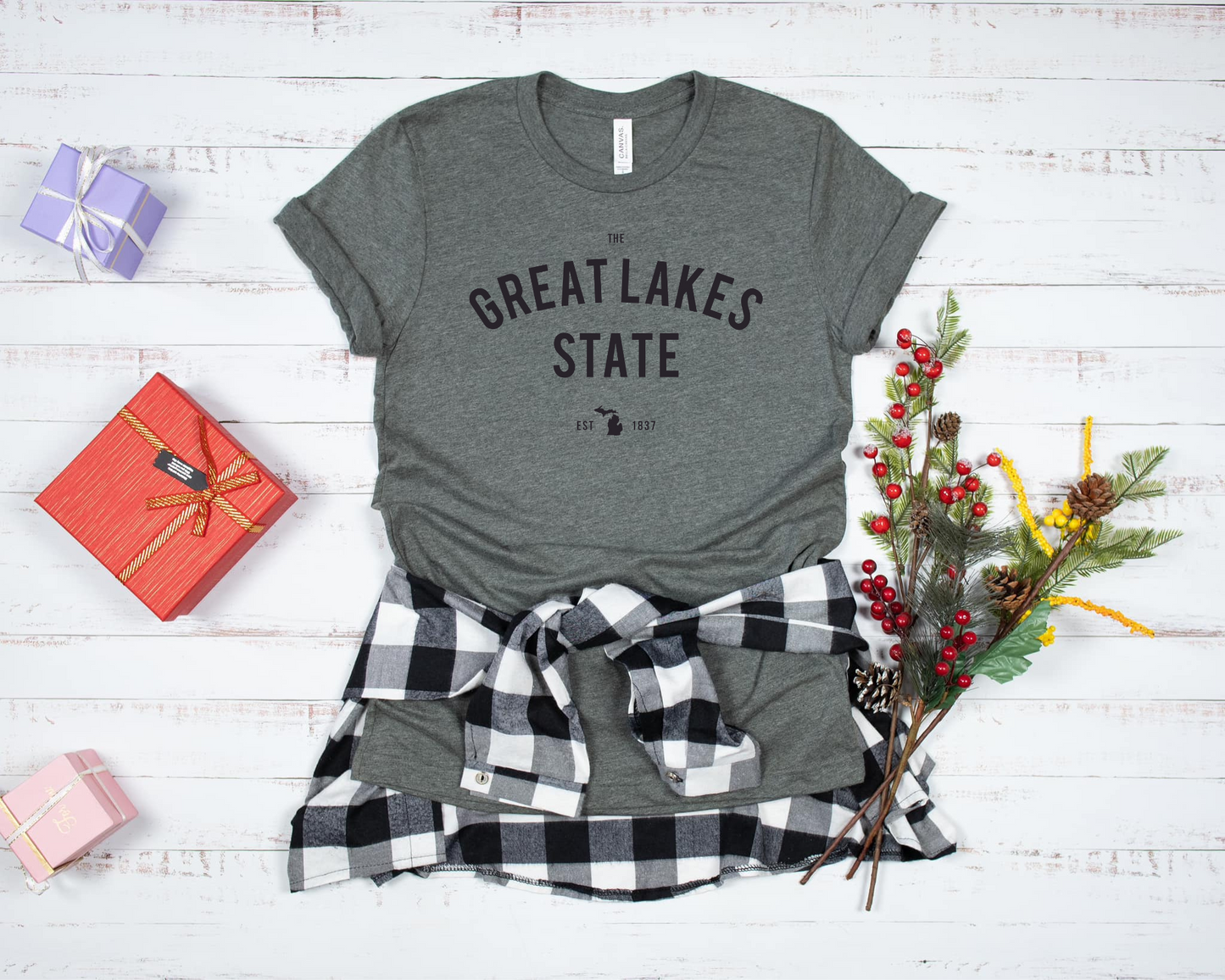 A classic dark grey tee with 'The Great Lakes State' printed across the front in bold, arched lettering. Below, a small Michigan silhouette and 'EST. 1837' add a subtle state pride detail. The design has a timeless, minimal look, making it perfect for anyone who loves Michigan and the Great Lakes.