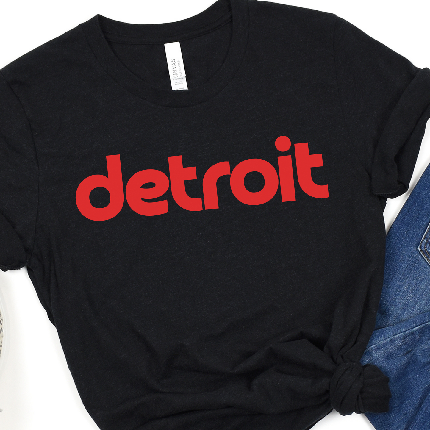 A black tee featuring the word 'detroit' in bold, modern red lowercase letters across the chest. The clean, minimalist design gives the sweatshirt a stylish and casual look, perfect for representing the Motor City in comfort and style