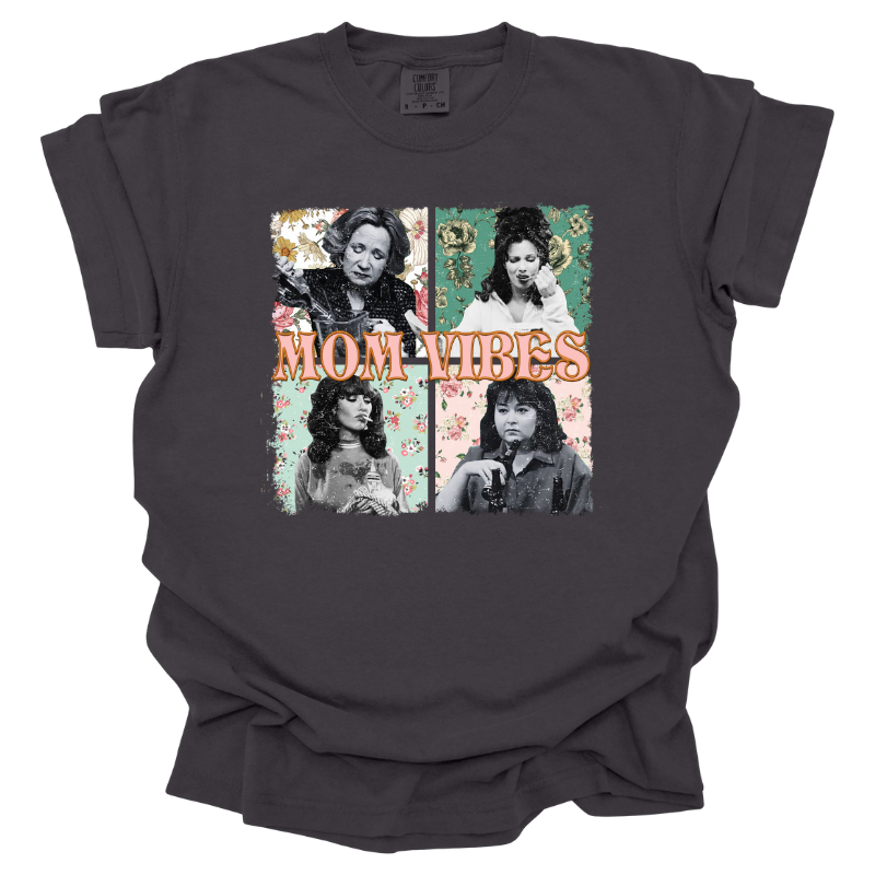 This Mom Vibes Tee is a graphite color T-shirt featuring tv mom icons Kitty Forman, Roseanne Connor, Sophia Petrillo, and Peggy Bundy each set against a retro floral background with old "mom vibes" text