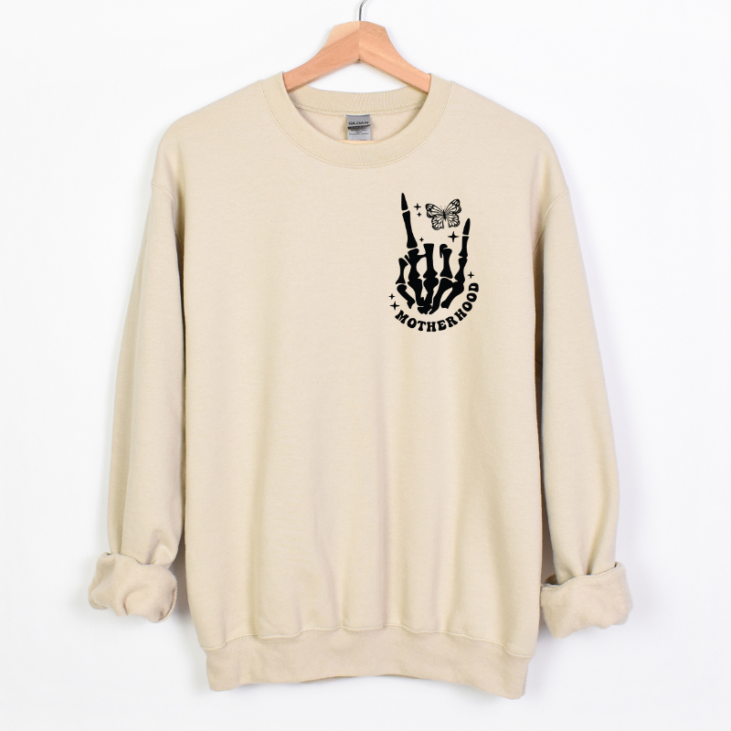 Natural Color Crewneck Sweatshirt with skeleton hand making rock sign with a butterfly, stars and the text "motherhood"