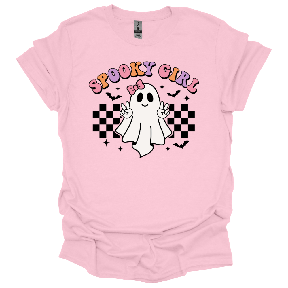 Pink youth Halloween shirt with a cute cartoon ghost throwing peace signs, surrounded by checkered patterns, bats, and the words “Spooky Girl” in fun pastel letters.