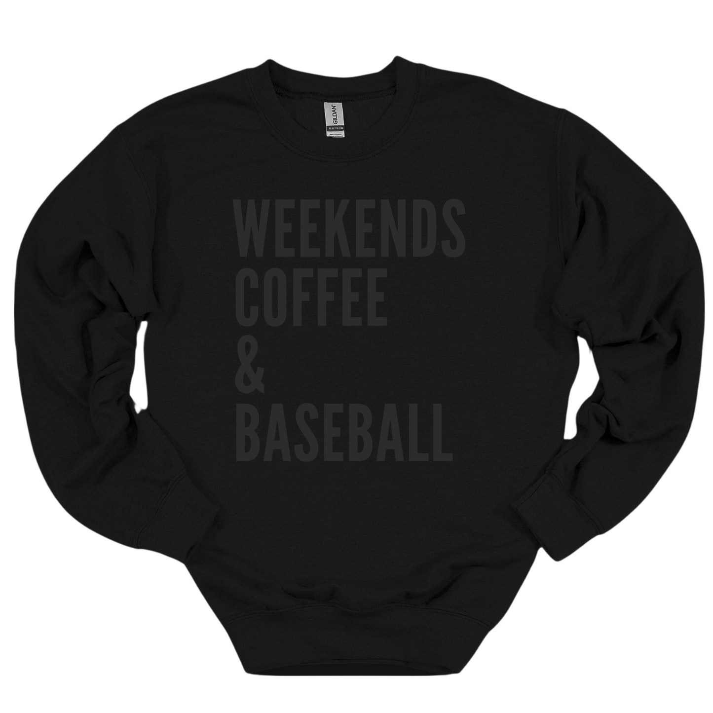 A black crewneck sweatshirt featuring bold black text that reads 'WEEKENDS, COFFEE & BASEBALL' stacked vertically in a simple, modern font. The cozy design is perfect for casual weekends and baseball lovers.