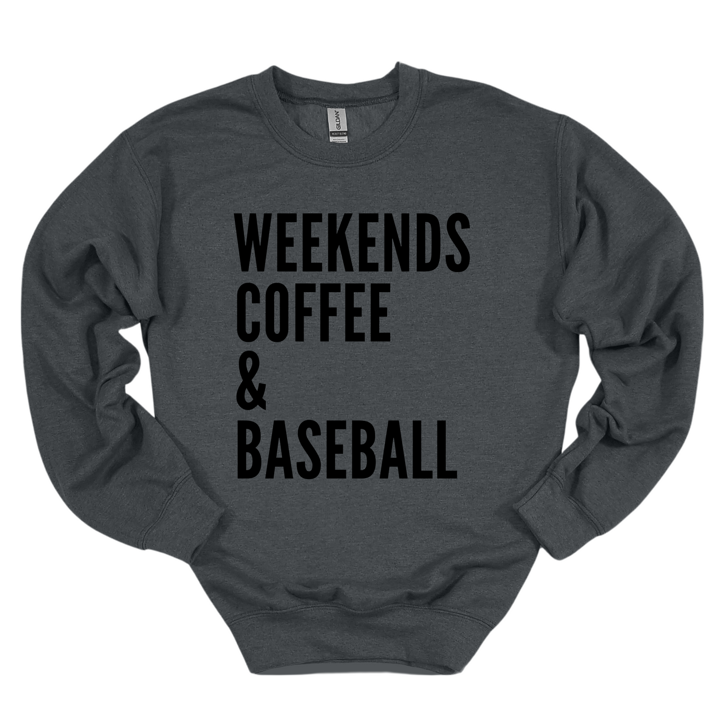 A dark gray crewneck sweatshirt featuring bold black text that reads 'WEEKENDS, COFFEE & BASEBALL' stacked vertically in a simple, modern font. The cozy design is perfect for casual weekends and baseball lovers.