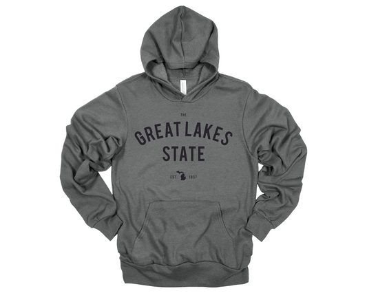 Cozy deep heather gray hoodie with Michigan pride design displayed in a modern, neutral-toned setting.