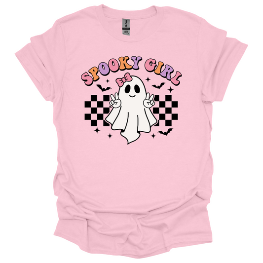 Pink youth Halloween shirt with a cute cartoon ghost throwing peace signs, surrounded by checkered patterns, bats, and the words “Spooky Girl” in fun pastel letters.